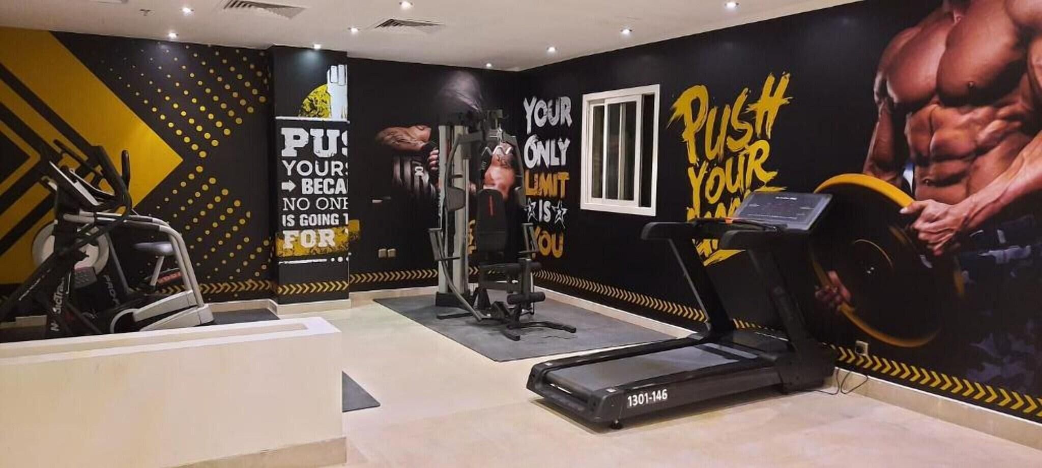 A gym with exercise equipment, motivational wall art, and a treadmill.