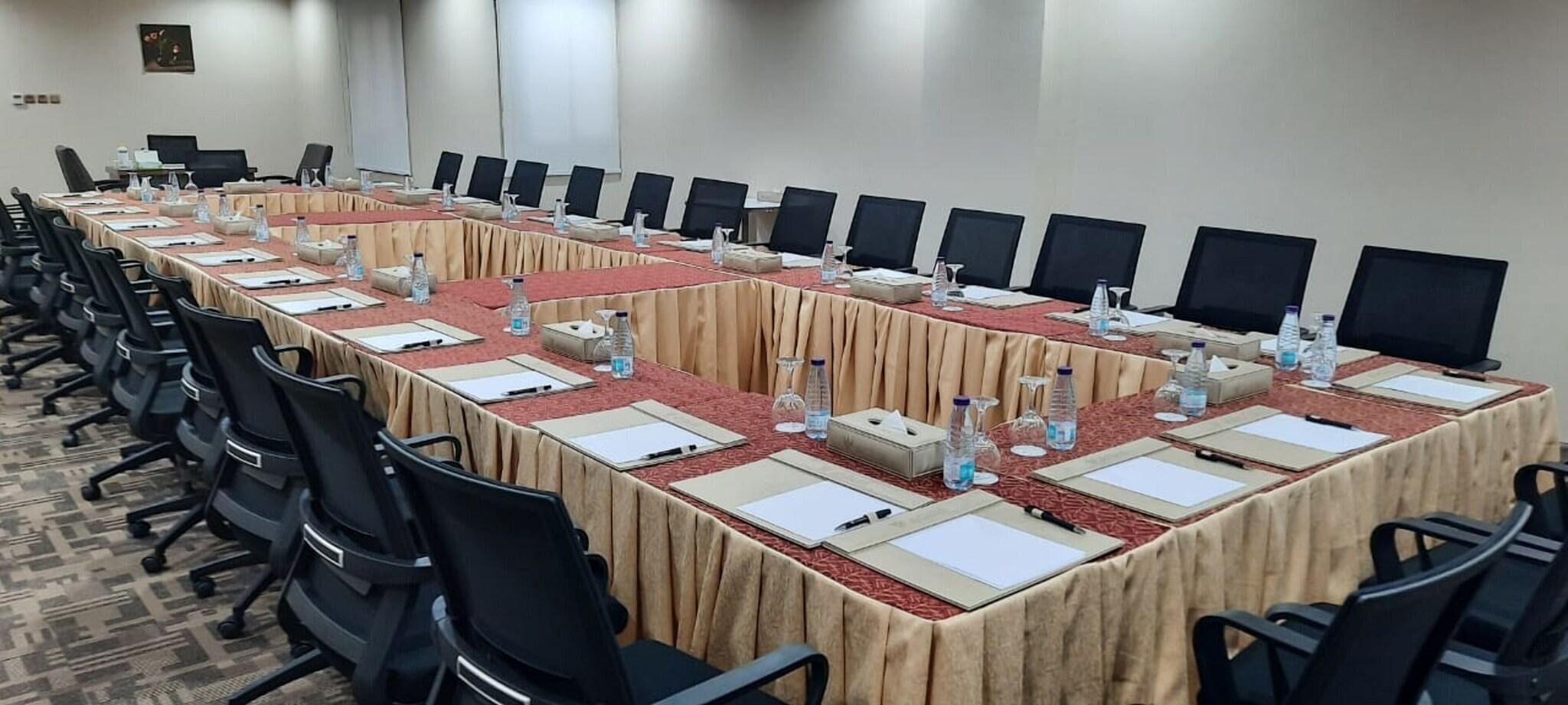 A conference room with a long table, chairs, water bottles, and nameplates.