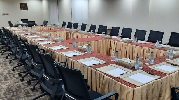 Een vergaderruimte met een lange tafel, stoelen, waterflesjes en naambordjes.