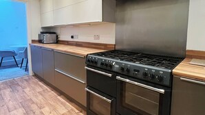 Una cocina moderna con extractor de acero inoxidable, dos hornos y un microondas.