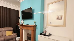 Una sala de estar con chimenea, un sofá, un televisor y un aparador.