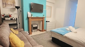 Un dormitorio moderno con sofá, cama, televisor, chimenea y un pasillo.