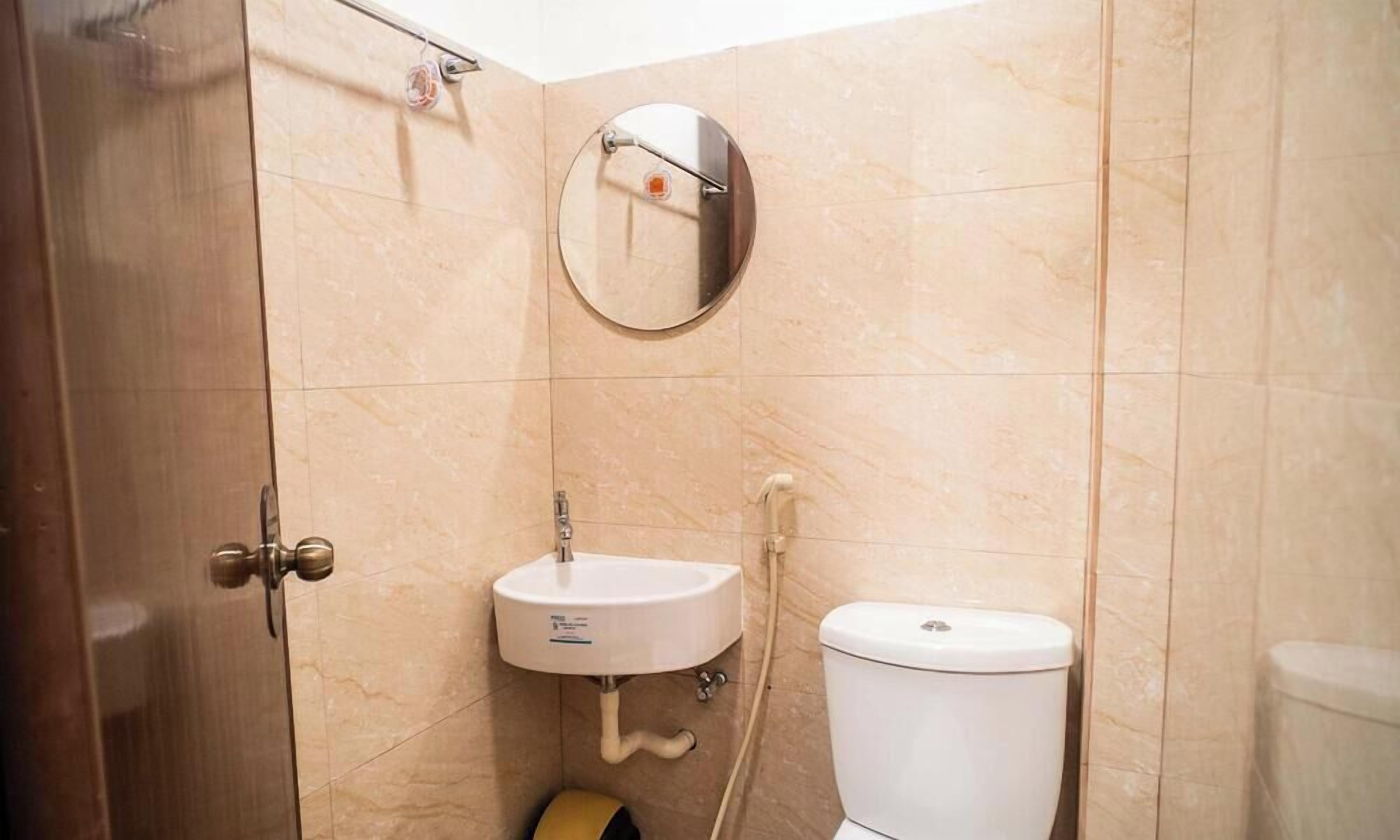 A bathroom with a toilet, sink, and mirror.