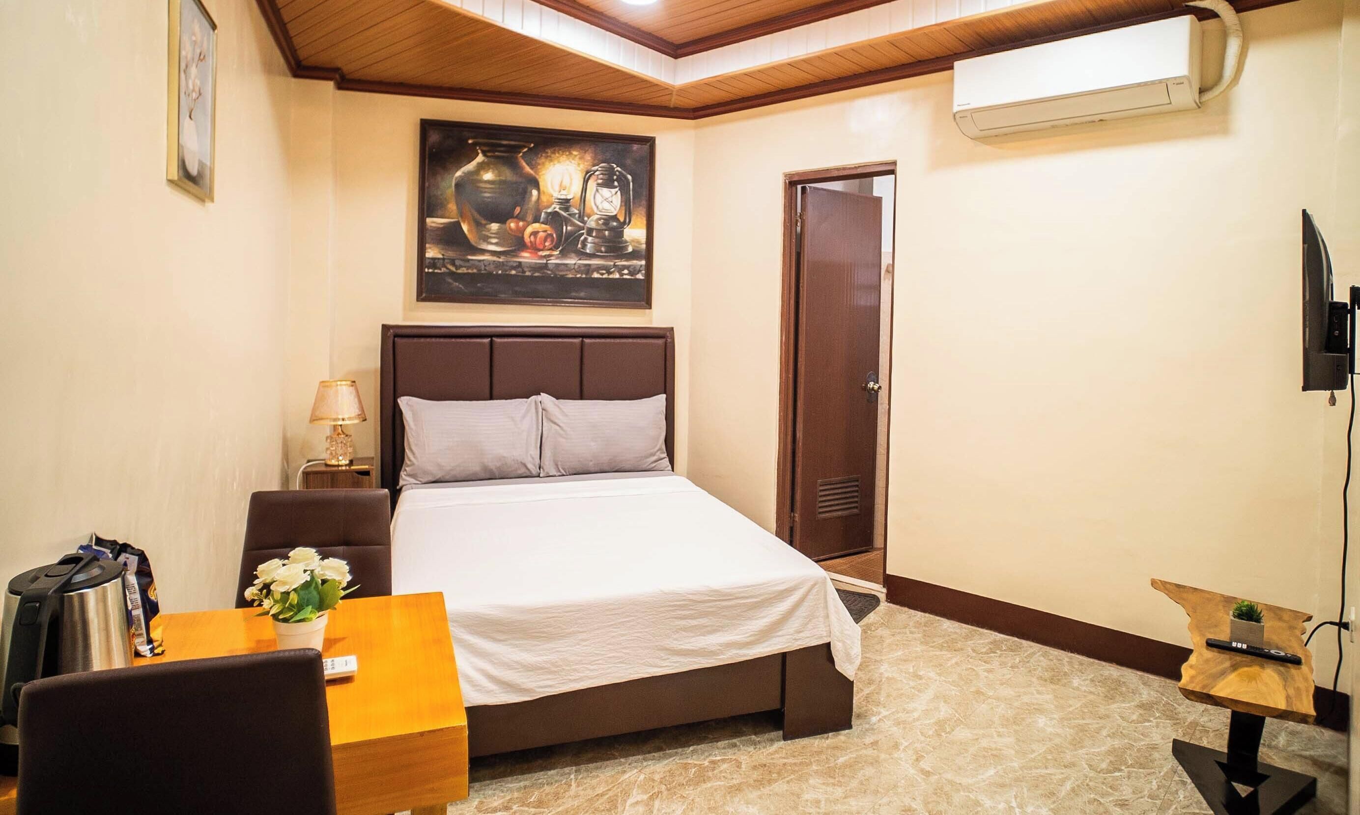 Une chambre d’hôtel avec un lit, une table de chevet, une lampe et un tableau au mur.