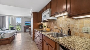 Una cocina moderna con encimeras de granito, armarios de madera, microondas integrado y un amplio ventanal con vista a la ciudad.