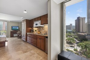 A modern kitchen with wooden cabinets, a microwave, and a sink. - Island Retreat at the Luana Waikiki (Honolulu)