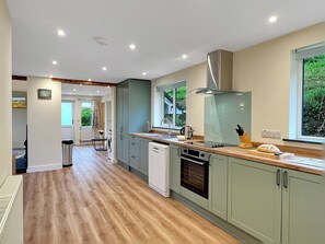 Una cucina moderna con pavimento in legno, elettrodomestici integrati e un'ampia finestra.