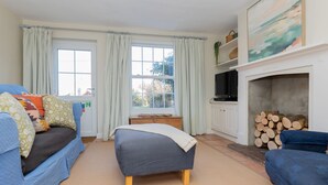 Ein gemütliches Zimmer mit einem Bett, zwei Sofas, einem Kamin und einem fenster mit Vorhängen.