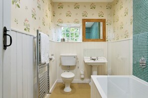 A bathroom with a toilet, sink, and bathtub, featuring floral wallpaper and a window. - High Swinton Cottage (Ripon)