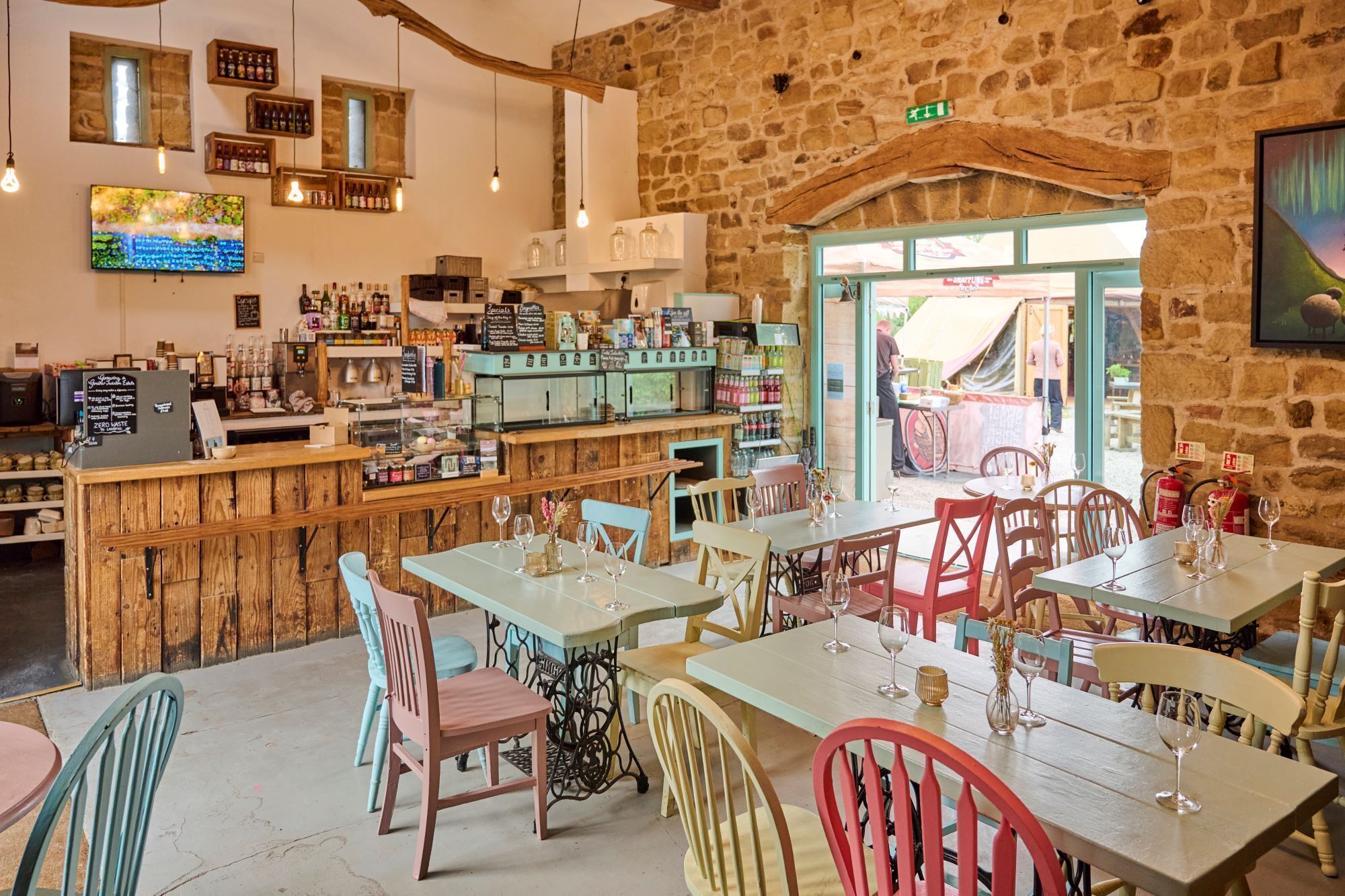 A rustic interior with wooden furniture, a bar area, and a stone wall.