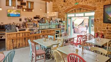 A rustic interior with wooden furniture, a bar area, and a stone wall.