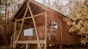 A rustic wooden cabin with a porch, large windows, and a chimney.