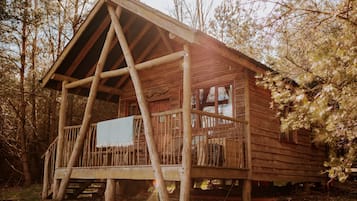 A rustic wooden cabin with a porch, large windows, and a chimney.