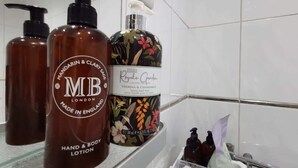 A bathroom with a hand and body lotion dispenser, a bottle of lotion, and a soap dispenser. - Spacious Clean Central Near Train Stn & University (Edinburgh)