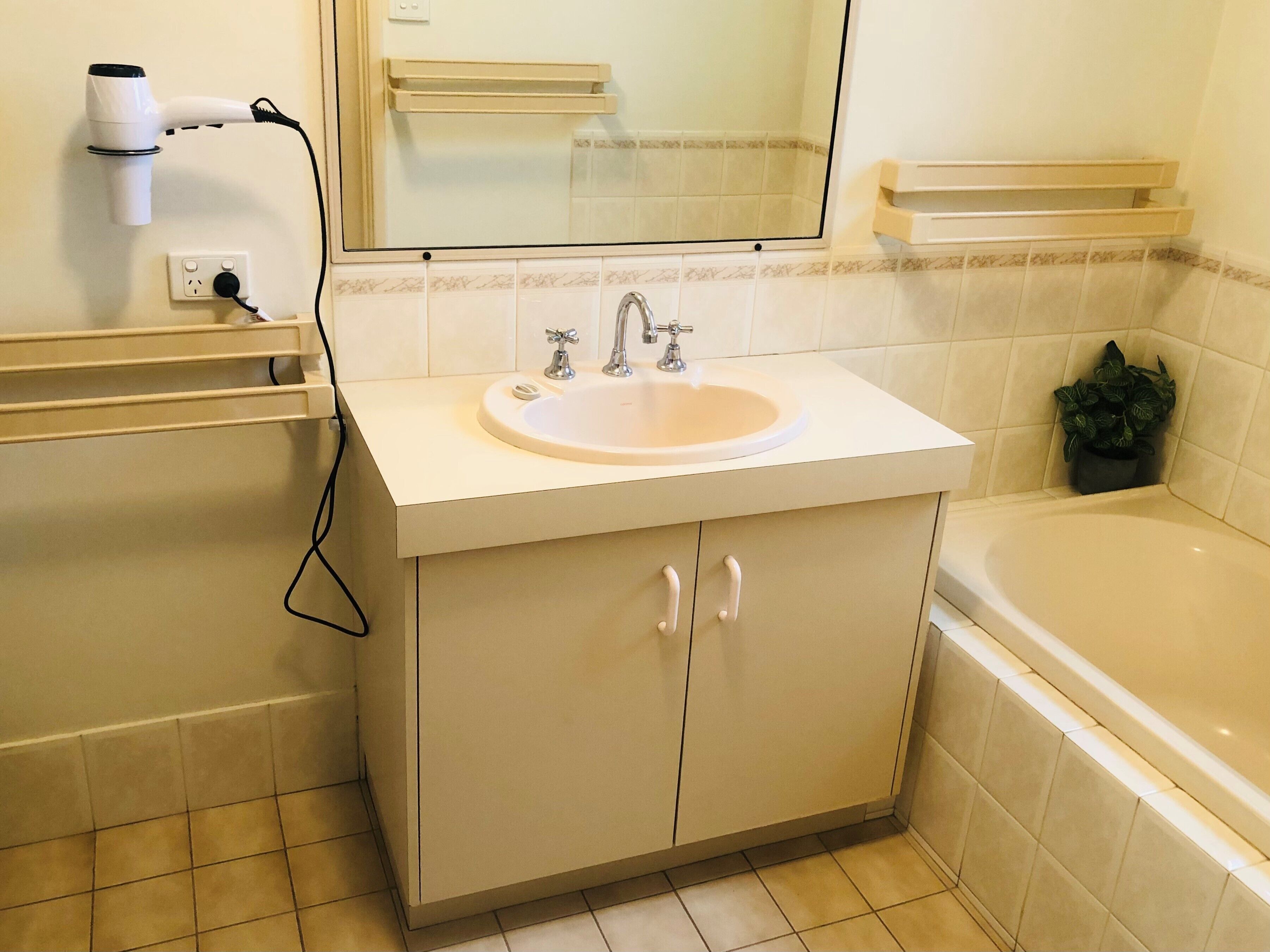 A bathroom with a sink, mirror, vanity, and a bathtub.