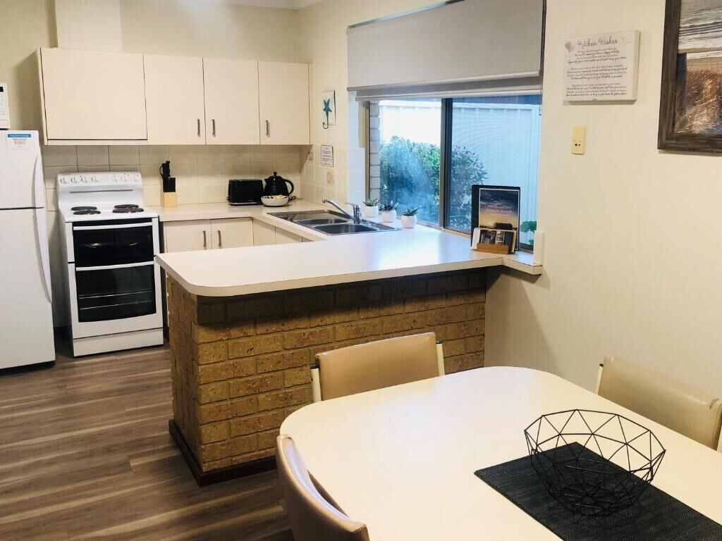 A kitchen with white cabinets, a stove, a sink, and a window.