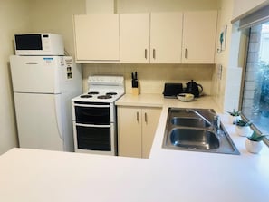 Una cocina con estufa, microondas, lavaplatos y armarios.