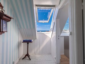 A narrow hallway with a skylight, a small table with a book, and a view of the sea. - 4 Star Holiday Home in Lokken (Lokken)