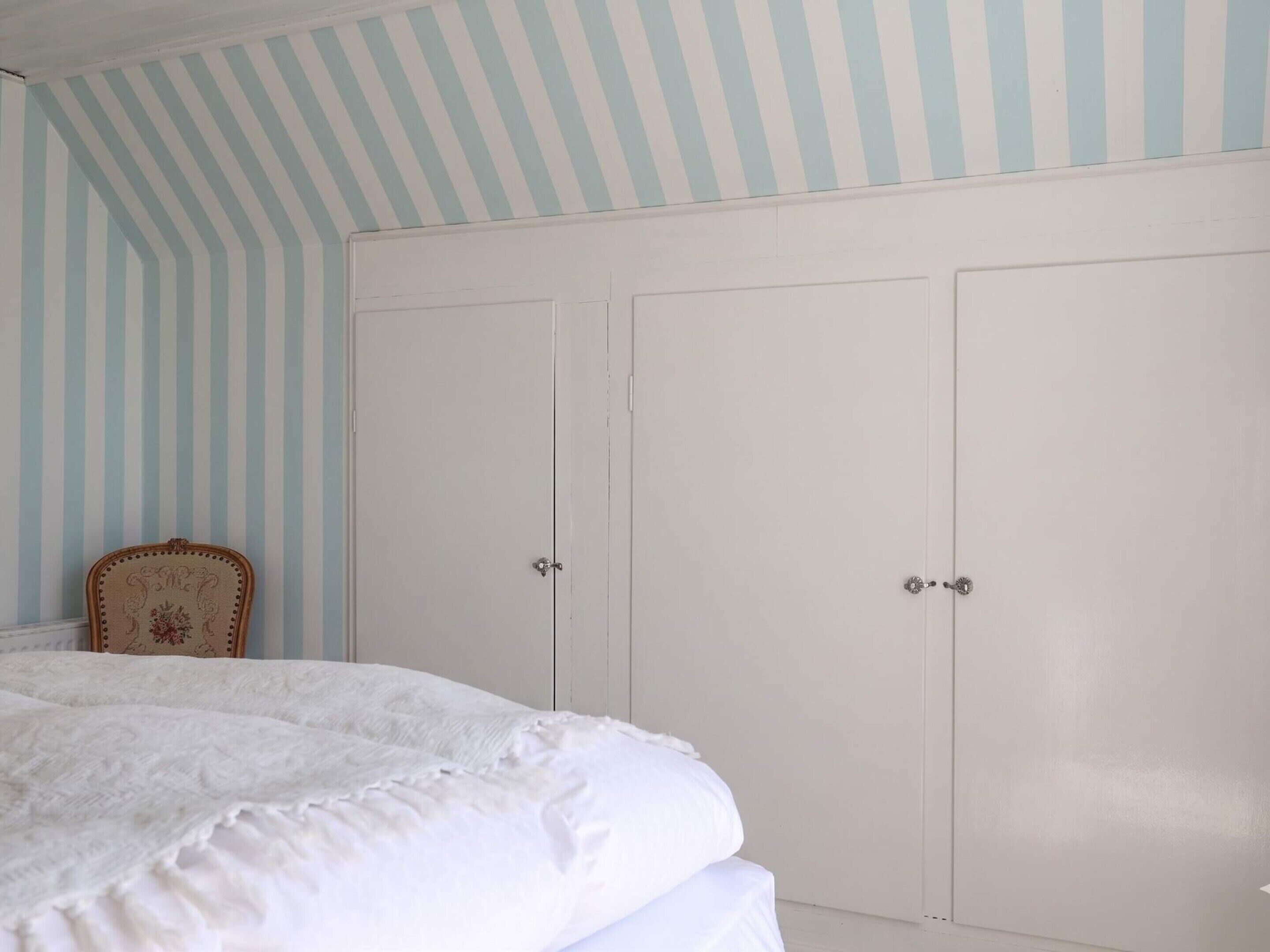 A bedroom with a bed, a chair, and a wardrobe.