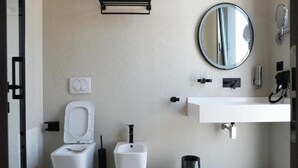 A modern bathroom with a toilet, bidet, sink, mirror, and a trash bin. - Hotel Star Light Tirane (Tirana)