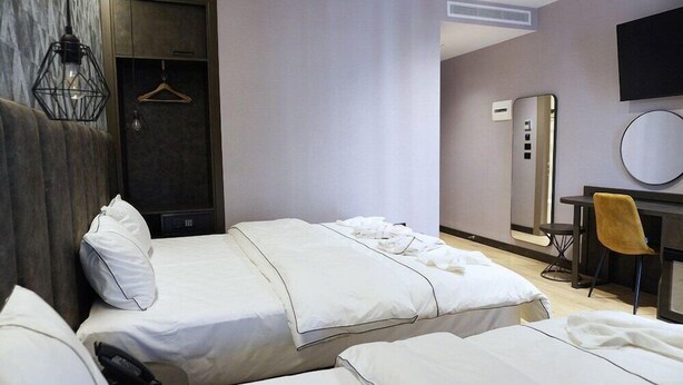 A hotel room with two beds, a desk, a mirror, and a hanging light fixture. - Hotel Star Light Tirane (Tirana)