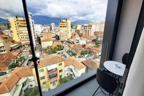 A room with a large window overlooking a cityscape with buildings and mountains. - Hotel Star Light Tirane (Tirana)