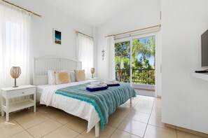 Ein Schlafzimmer mit einem Bett, Nachttischen, einem Fenster mit Blick und einem Fernseher.