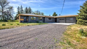 A modern two-story house with a gravel driveway and a garage. - Rock Creek Canyon | 1BR, Hot Tub, Sauna, Fire Pit (Twin Falls)