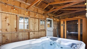 A wooden cabin interior with a hot tub, wooden walls, and a door leading outside. - Rock Creek Canyon | 1BR, Hot Tub, Sauna, Fire Pit (Twin Falls)
