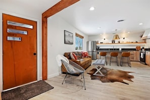 A modern kitchen with a central island, bar stools, and a dining area.