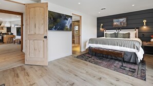 A modern bedroom with a large bed, a dark accent wall, and a painting. - Rock Creek Canyon | 1BR, Hot Tub, Sauna, Fire Pit (Twin Falls)