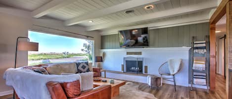 A living room with a leather sofa, a fireplace, and a television mounted on the wall.