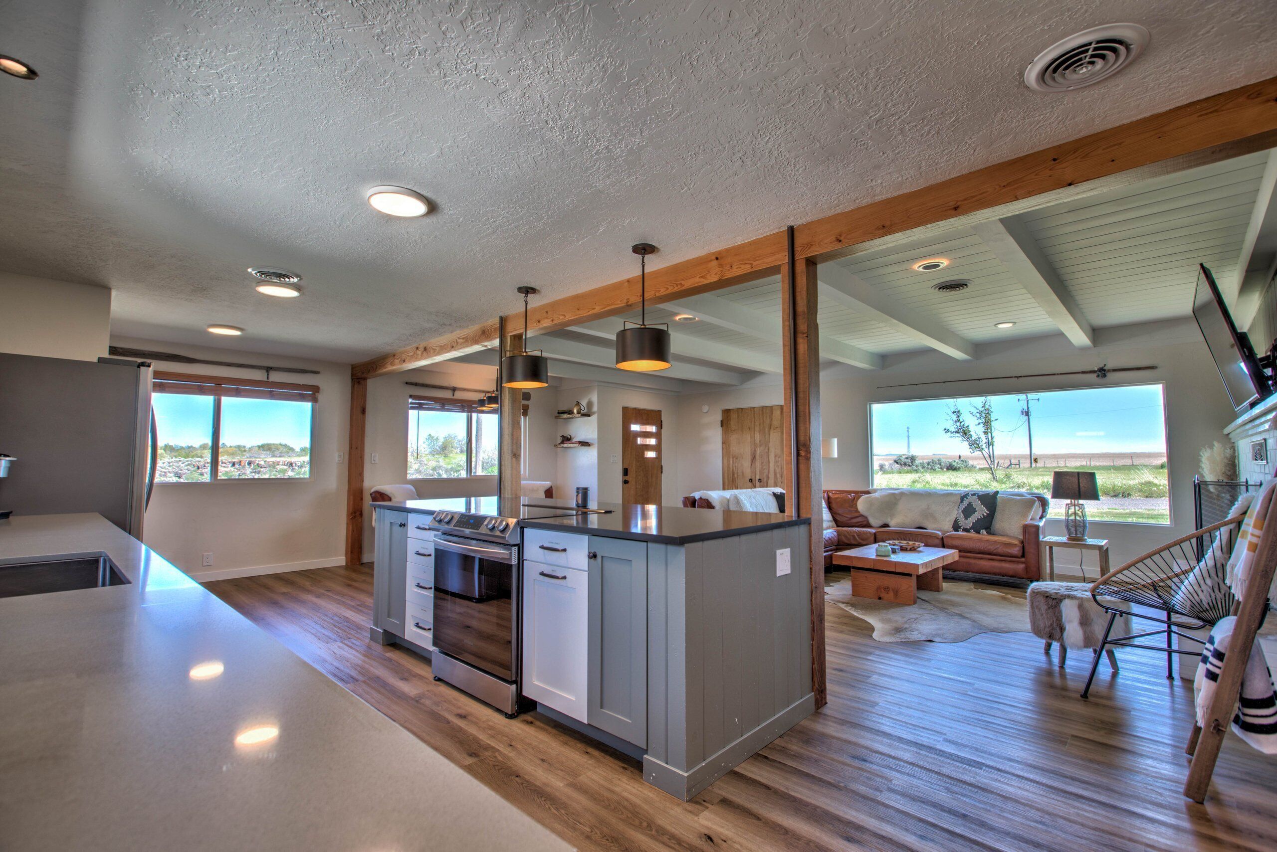 Una cocina moderna con una isla central, vigas de madera y vistas al exterior.