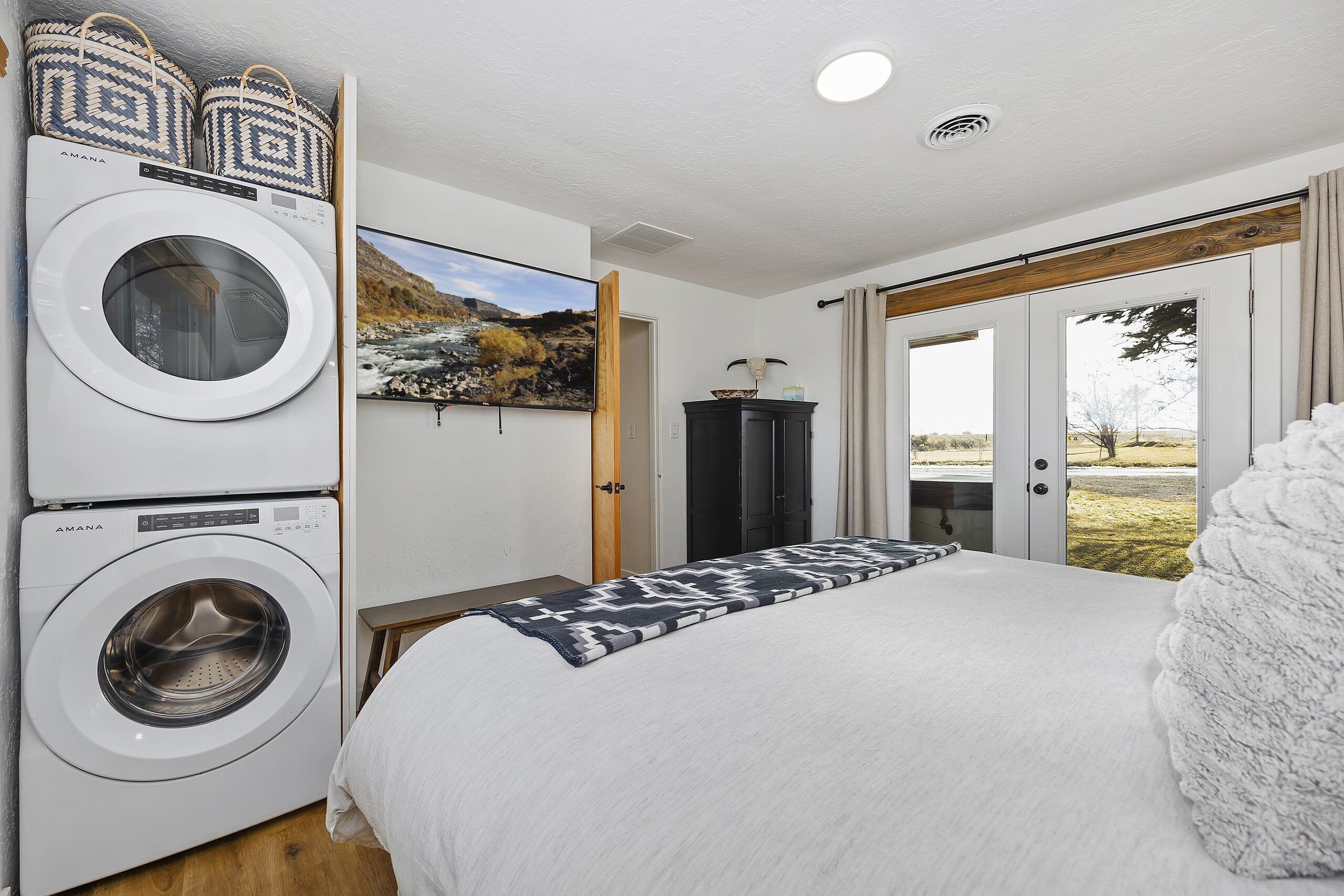 Une chambre d’hôtel équipée d’un lit, d’une machine à laver, d’une télévision et offrant une vue sur l’extérieur.