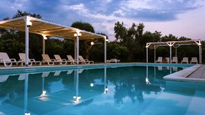 Piscina com espreguiçadeiras e área coberta.