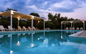 Una piscina con sillones de descanso y una zona cubierta.