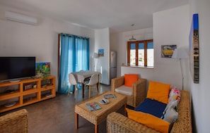 A living room with a television, wicker furniture, a dining area with a table and chairs, and a refrigerator. - 2 bedroom gorgeous apartment in Pizzo (Pizzo)