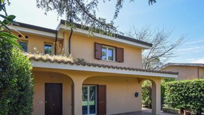 Une maison à deux étages avec un patio couvert, une porte d’entrée et un petit jardin.