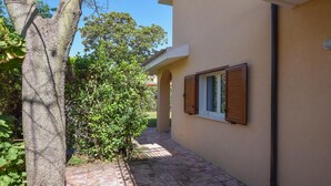 Un étroit sentier mène à un bâtiment doté d’une fenêtre et d’un arbre situé sur la gauche.