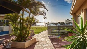 A patio with outdoor seating, a palm tree, and a view of the sea.