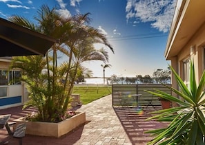 Un patio con mobiliario exterior, una palmera y vista al mar.