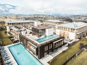 Un hotel moderno con varias construcciones, piscina y vistas a las montañas.