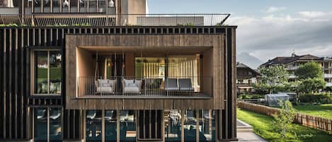 A modern house with a pool, large windows, and a balcony with outdoor seating.