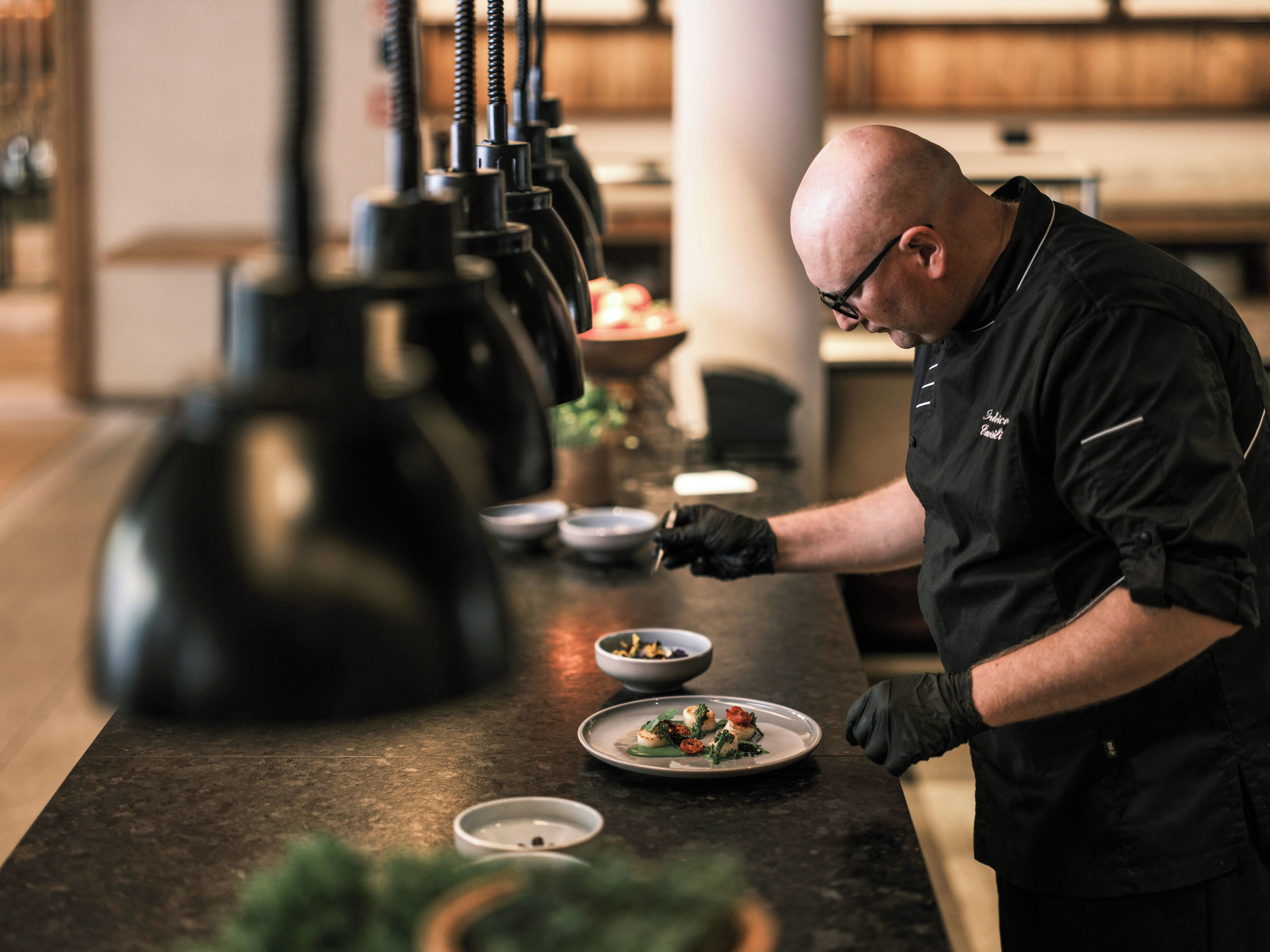 A chef preparing food in a kitchen with a marble countertop and modern appliances.