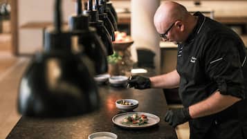 A chef preparing food in a kitchen with a marble countertop and modern appliances.