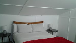 A hotel room with a bed, two bedside tables, and a red blanket.