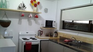 A kitchen with a stove, microwave, sink, and various kitchen items.