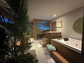 Un baño moderno con bañera, banco de madera y plantas en macetas.