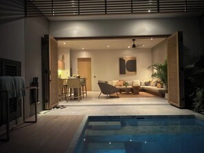 Un interior modern amb una piscina, zona de menjador i saló amb sofà i taula de centre.