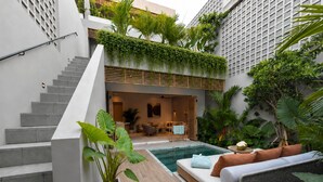 A modern outdoor living space with a pool, a staircase, and a seating area with cushions. - Sin Nombre Homes  (Badung)